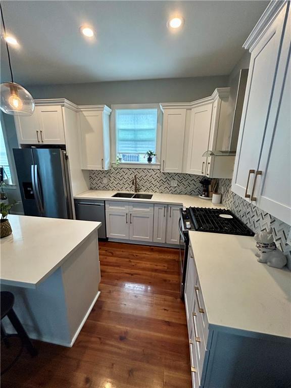 kitchen with white cabinetry, sink, dark wood-type flooring, pendant lighting, and appliances with stainless steel finishes