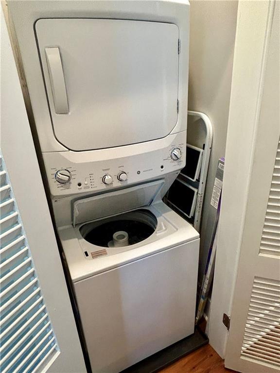 laundry area featuring hardwood / wood-style floors and stacked washing maching and dryer