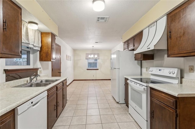 kitchen featuring white appliances, sink, light tile patterned floors, an inviting chandelier, and hanging light fixtures