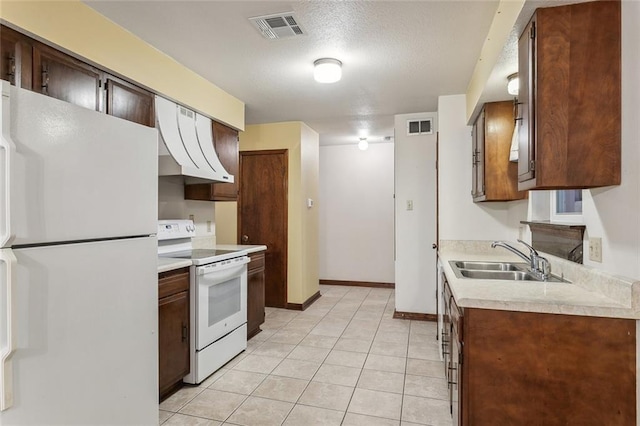 kitchen with light tile patterned floors, white appliances, a textured ceiling, and sink