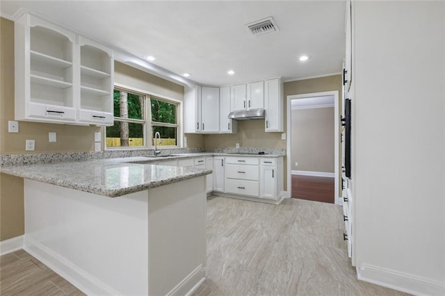 kitchen with light stone counters, visible vents, under cabinet range hood, and white cabinetry