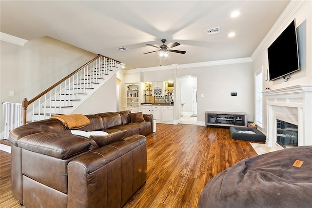 living room featuring a fireplace, hardwood / wood-style floors, ceiling fan, and ornamental molding