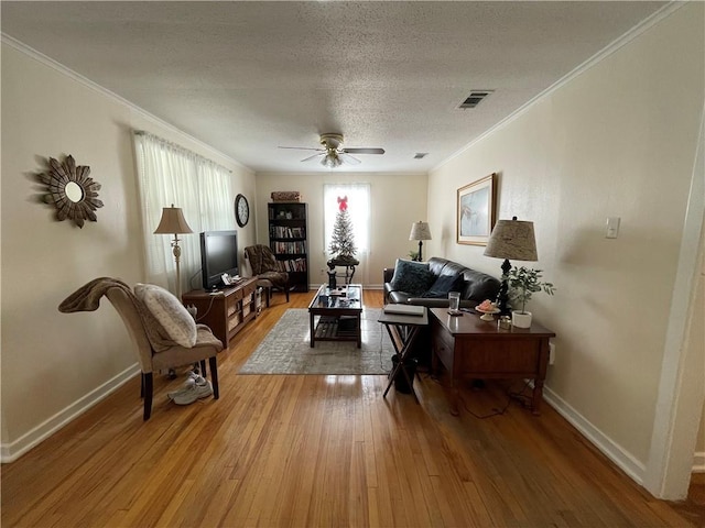 living room featuring wood-type flooring, plenty of natural light, crown molding, and ceiling fan