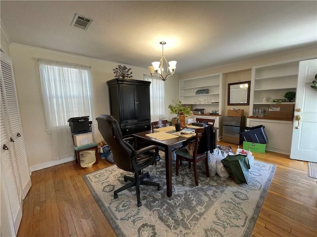 dining space with hardwood / wood-style floors, a textured ceiling, crown molding, and a notable chandelier