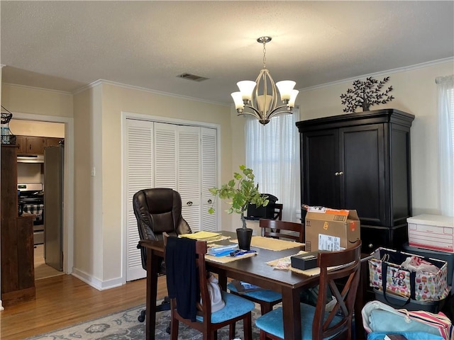 dining area featuring hardwood / wood-style floors, ornamental molding, and an inviting chandelier