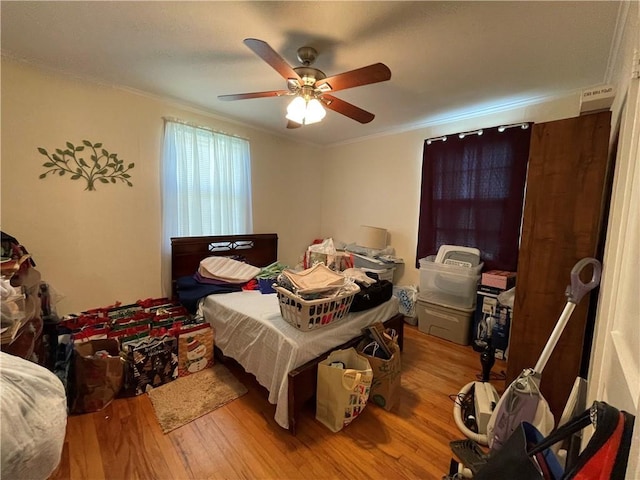 bedroom featuring hardwood / wood-style floors, ceiling fan, and crown molding