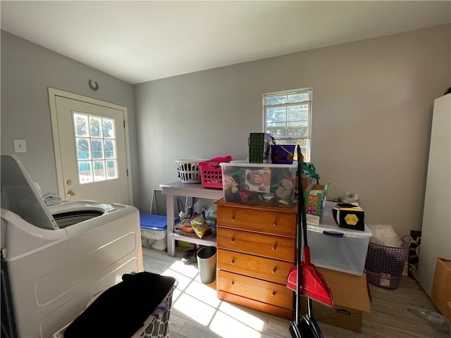 bedroom with light hardwood / wood-style floors, washing machine and dryer, and multiple windows