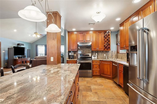 kitchen with light stone countertops, ceiling fan, sink, hanging light fixtures, and stainless steel appliances