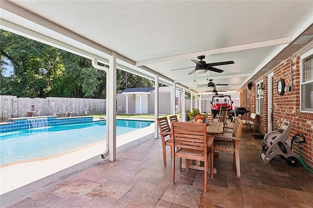 view of pool with a patio, pool water feature, and a shed