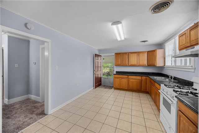 kitchen featuring light tile patterned floors, white gas range, ornamental molding, and sink