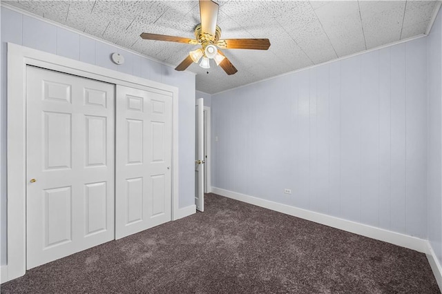 unfurnished bedroom with ceiling fan, dark carpet, and a closet