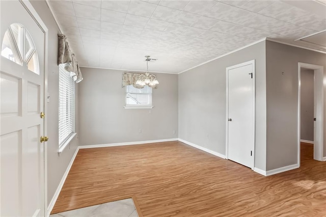 empty room featuring an inviting chandelier, ornamental molding, and hardwood / wood-style flooring