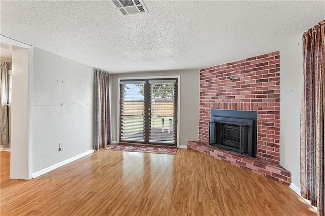 unfurnished living room with a fireplace, a textured ceiling, and light hardwood / wood-style flooring