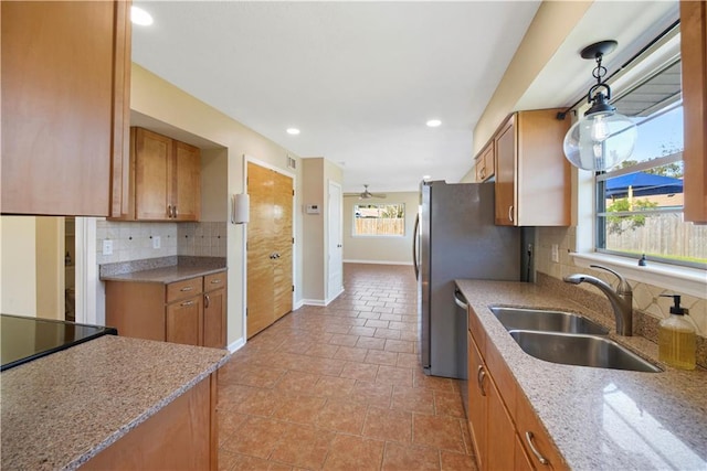 kitchen featuring pendant lighting, light stone counters, sink, and a healthy amount of sunlight