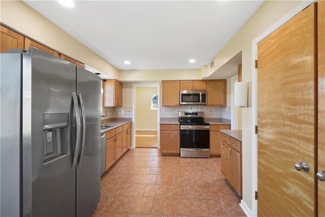 kitchen with light tile patterned floors, stainless steel appliances, tasteful backsplash, and sink