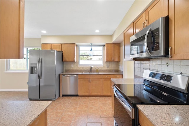 kitchen featuring backsplash, light stone counters, sink, and appliances with stainless steel finishes