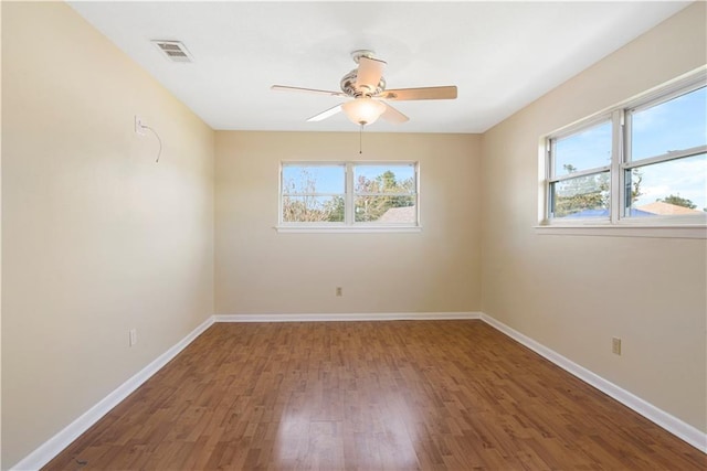 spare room with a wealth of natural light, hardwood / wood-style floors, and ceiling fan