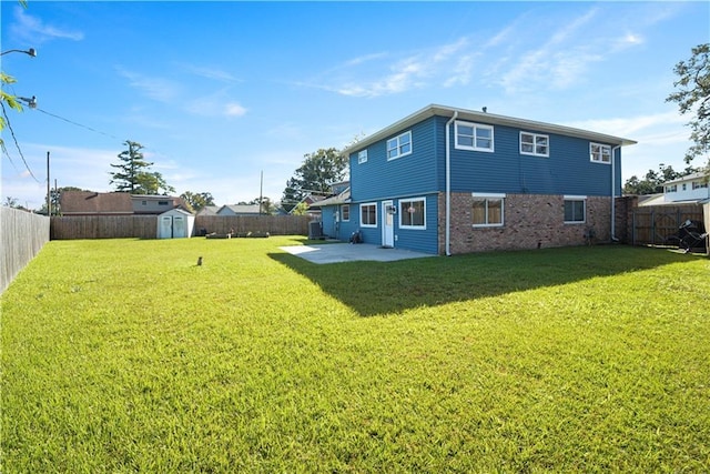 back of house featuring a yard, a patio, and a shed