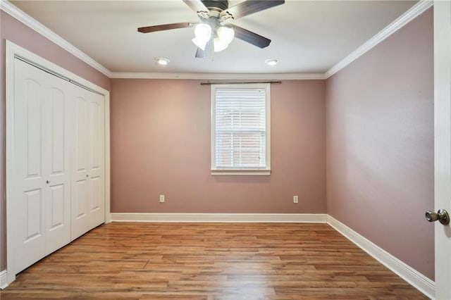 unfurnished bedroom with ceiling fan, a closet, ornamental molding, and light wood-type flooring