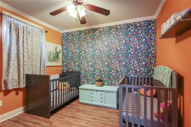 bedroom featuring light wood-type flooring, a nursery area, and ceiling fan