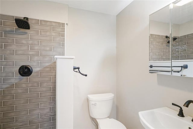 bathroom featuring tiled shower, sink, and toilet