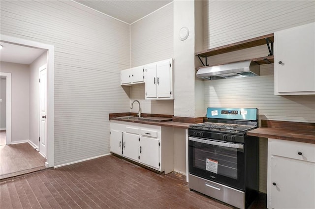 kitchen with white cabinets, stainless steel gas range oven, dark hardwood / wood-style flooring, and wall chimney range hood