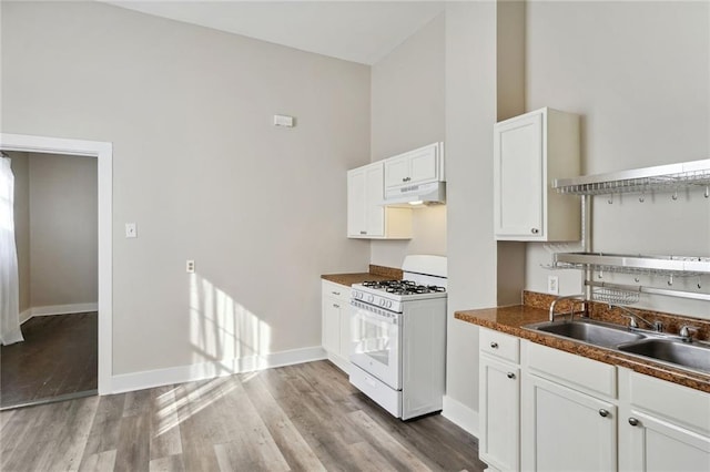 kitchen featuring white cabinetry, gas range gas stove, sink, a high ceiling, and light hardwood / wood-style floors