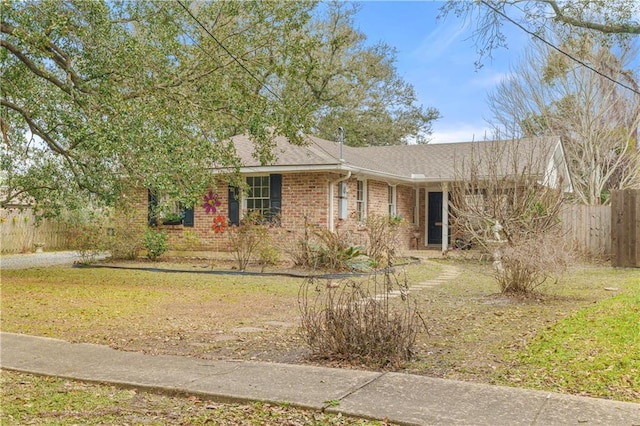 ranch-style house with brick siding, a front yard, fence, and a shingled roof