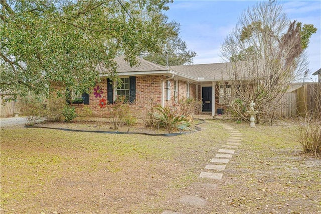 ranch-style home with brick siding, fence, and a front lawn