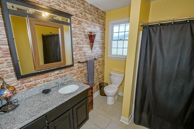 bathroom with tile patterned flooring, vanity, toilet, and brick wall