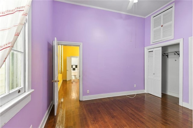 unfurnished bedroom with a closet, dark hardwood / wood-style flooring, ceiling fan, and crown molding