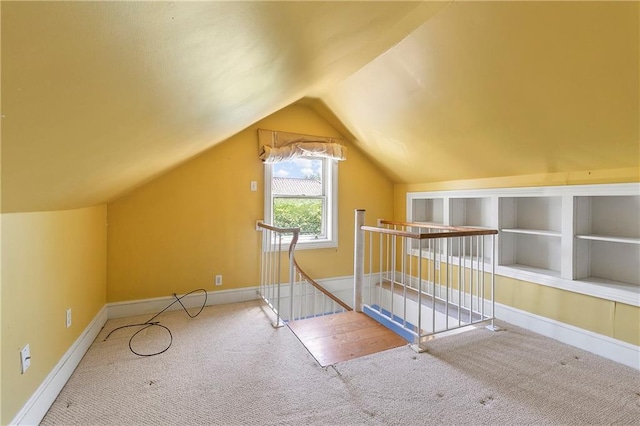 bonus room featuring built in shelves, carpet floors, and vaulted ceiling