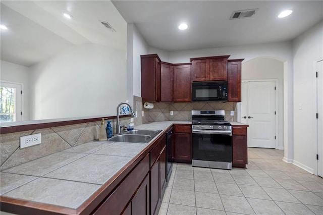 kitchen featuring decorative backsplash, sink, tile countertops, stainless steel gas stove, and light tile patterned flooring