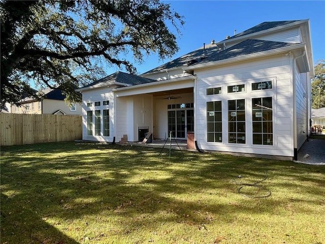 rear view of property featuring a lawn and ceiling fan