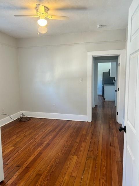 empty room with hardwood / wood-style flooring and ceiling fan