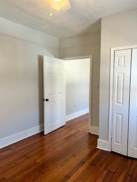 unfurnished bedroom with a textured ceiling, ceiling fan, a closet, and dark hardwood / wood-style floors