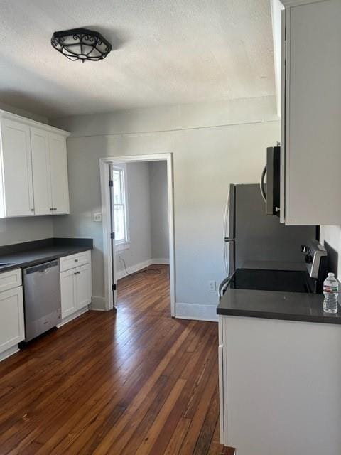 kitchen featuring white cabinets, dark hardwood / wood-style flooring, stainless steel appliances, and a textured ceiling