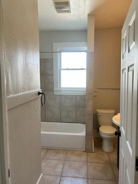 bathroom featuring tile patterned floors, tiled shower / bath, and toilet