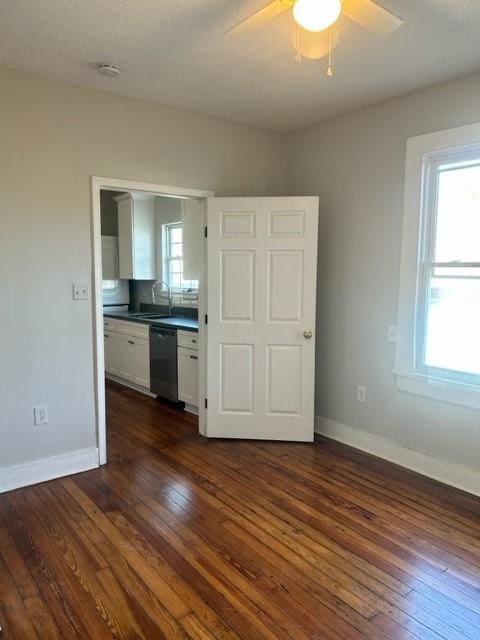 spare room with a wealth of natural light, dark hardwood / wood-style flooring, and ceiling fan