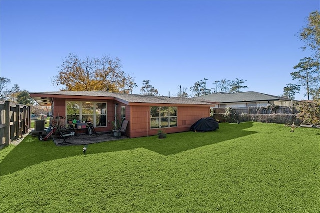 rear view of house featuring a lawn and central air condition unit