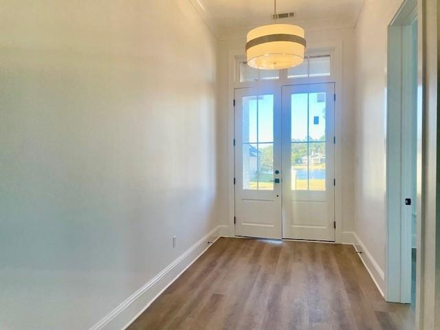 entryway with hardwood / wood-style floors, crown molding, and french doors