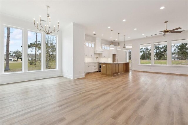 unfurnished living room featuring ceiling fan with notable chandelier, light hardwood / wood-style floors, and sink