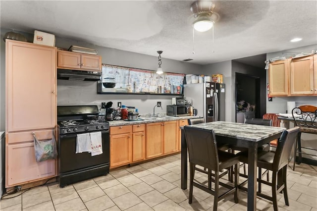1910B Charbonnet St, New Orleans, LA 70117 - kitchen featuring under cabinet range hood, stainless steel appliances, light tile patterned floors, light brown cabinets, and ceiling fan