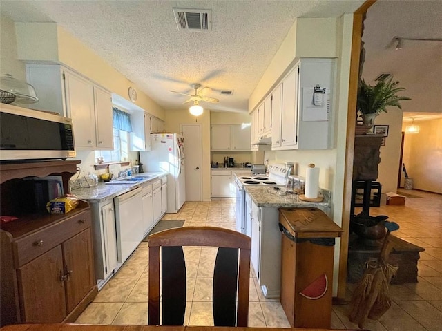 kitchen with white cabinets, light tile patterned flooring, white appliances, and a textured ceiling