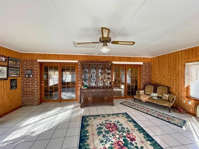 interior space with light tile patterned flooring, ceiling fan, and wood walls