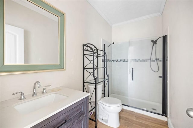 bathroom featuring hardwood / wood-style floors, vanity, crown molding, toilet, and an enclosed shower