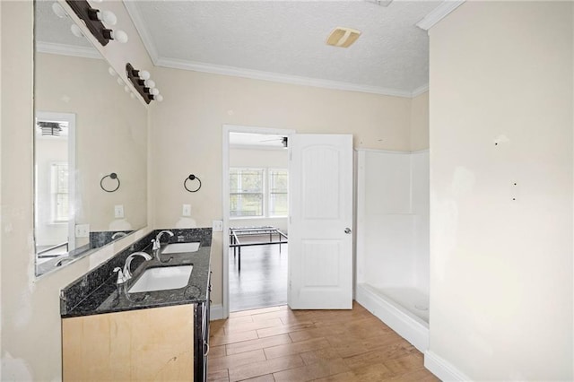 bathroom featuring ornamental molding, vanity, a textured ceiling, ceiling fan, and hardwood / wood-style flooring