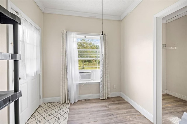 interior space with light wood-type flooring, cooling unit, and ornamental molding