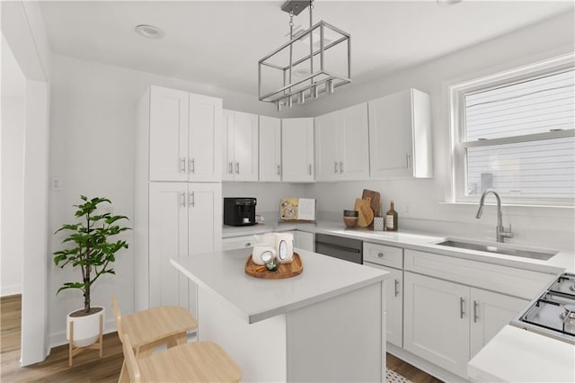 kitchen with a breakfast bar, white cabinets, sink, hanging light fixtures, and a kitchen island