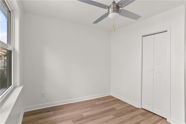 unfurnished bedroom featuring ceiling fan, light wood-type flooring, and a closet